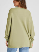 Person wearing a green ribbed sweater on a white background