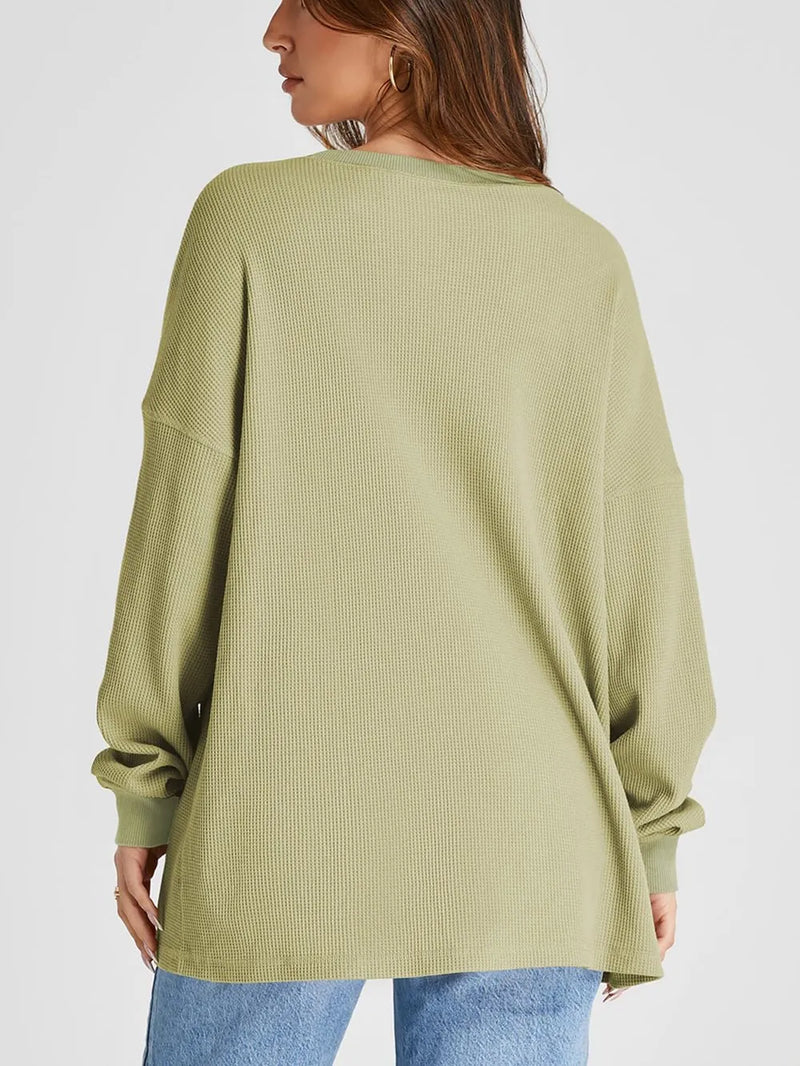 Person wearing a green ribbed sweater on a white background