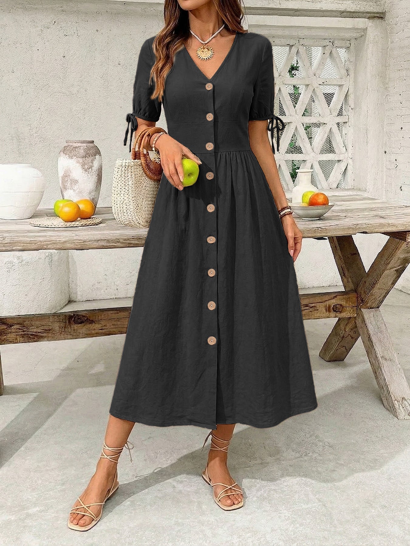 Woman wearing a black dress with buttons in an outdoor setting.