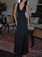 Woman in a long black dress standing in an ornate room with floral patterns on the walls and furniture.