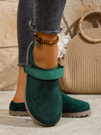 Green suede shoes worn with gray jeans against a neutral background