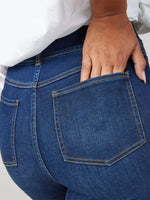 Close-up of blue jeans with a hand in the pocket against a white background