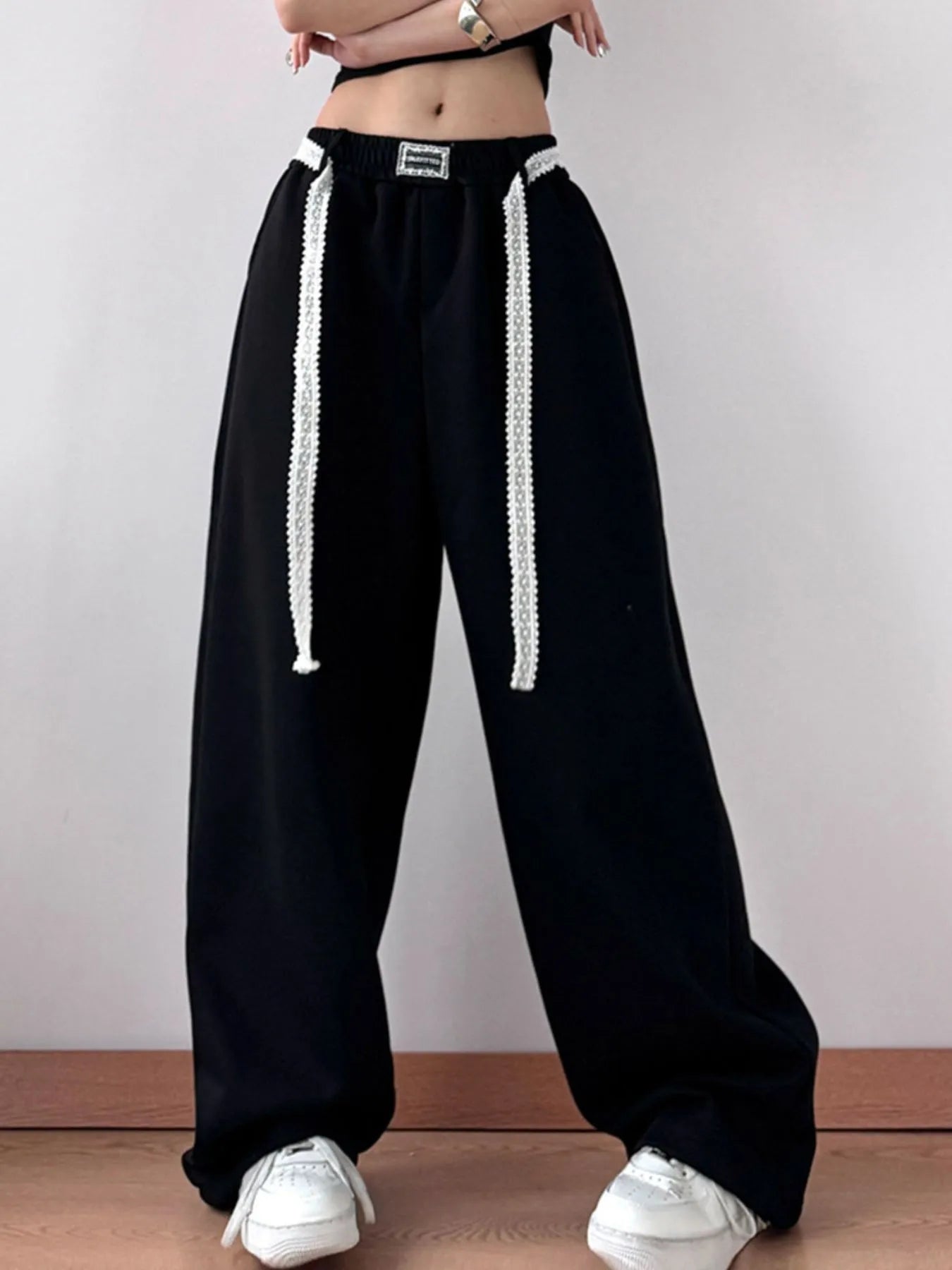 Black wide-leg pants with white drawstrings worn by a person on a plain background