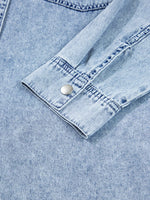 Close-up of a light blue denim shirt with a button on a matching fabric background