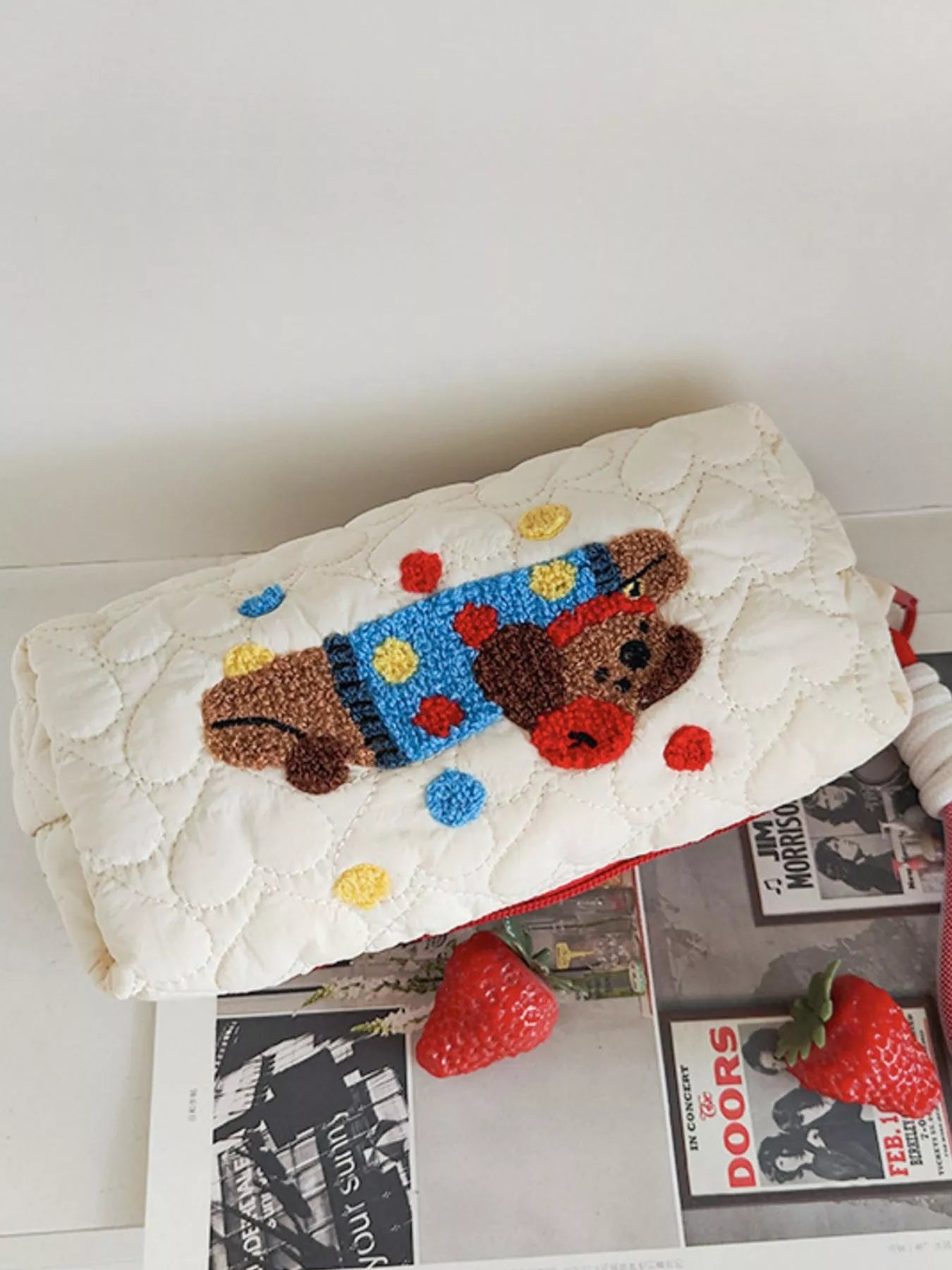 Doormat with a cartoon dog design on a white surface with magazines and strawberries.
