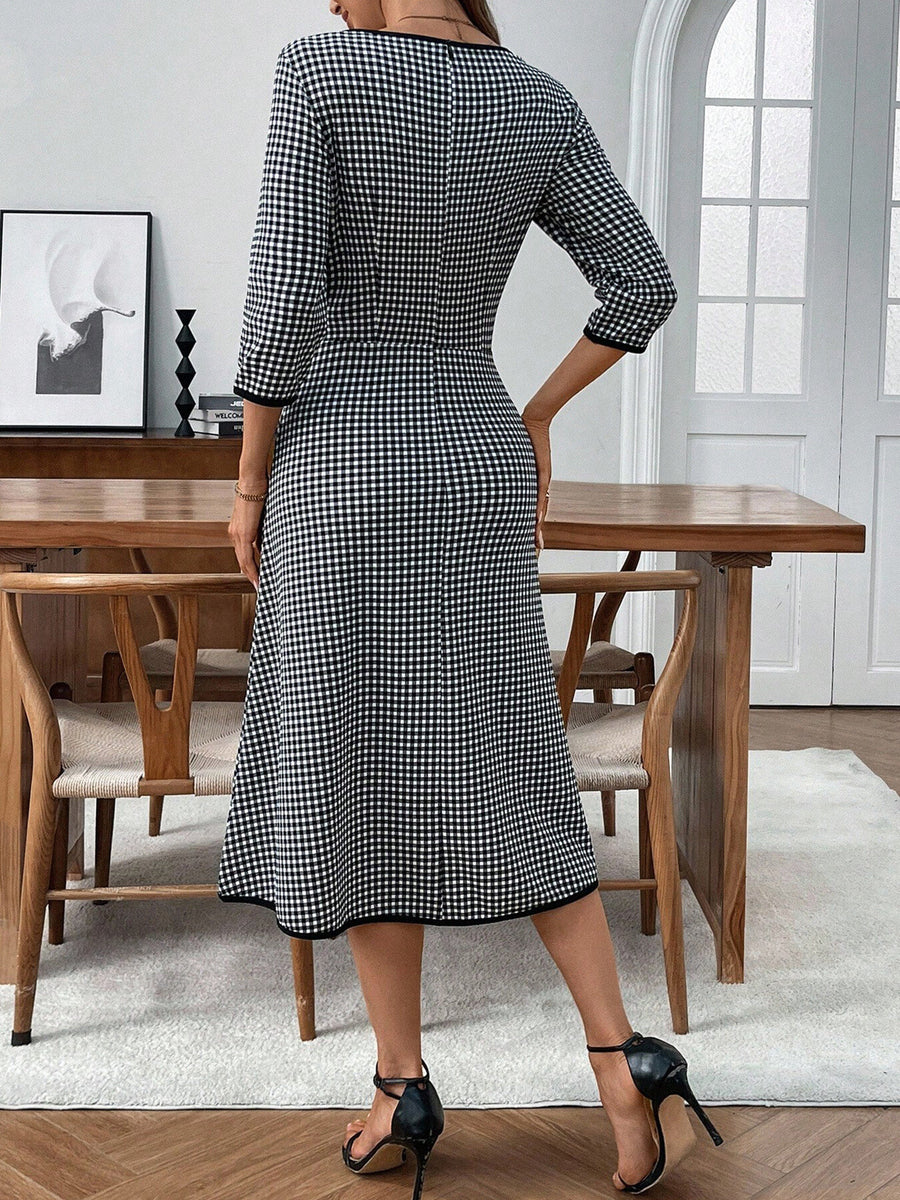 Woman wearing a black and white checkered dress in a dining room setting.