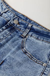 Close-up of blue denim fabric with a button and stitching detail.
