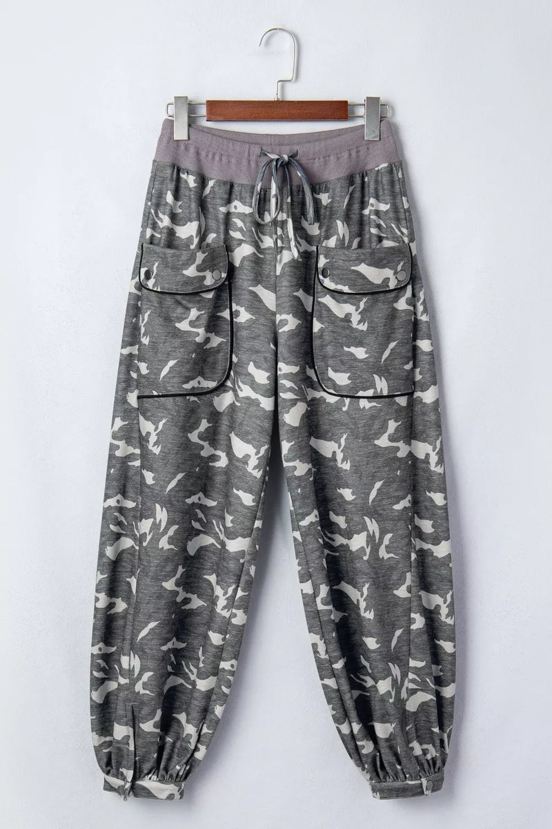 Gray camouflage pants on a hanger against a white background