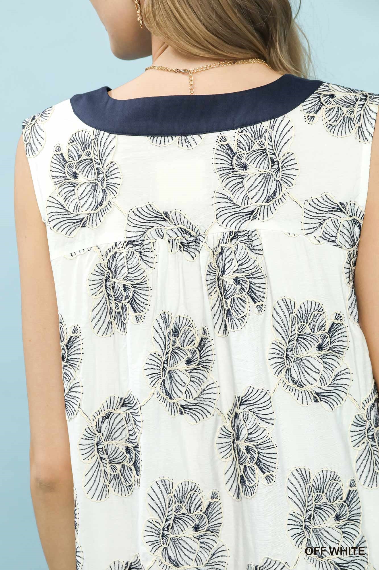 White sleeveless top with black floral pattern on a light blue background