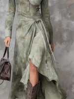 Person wearing a long, light green dress with a textured surface, holding a matching handbag against a gray background.