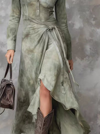 Person wearing a long, light green dress with a textured surface, holding a matching handbag against a gray background.
