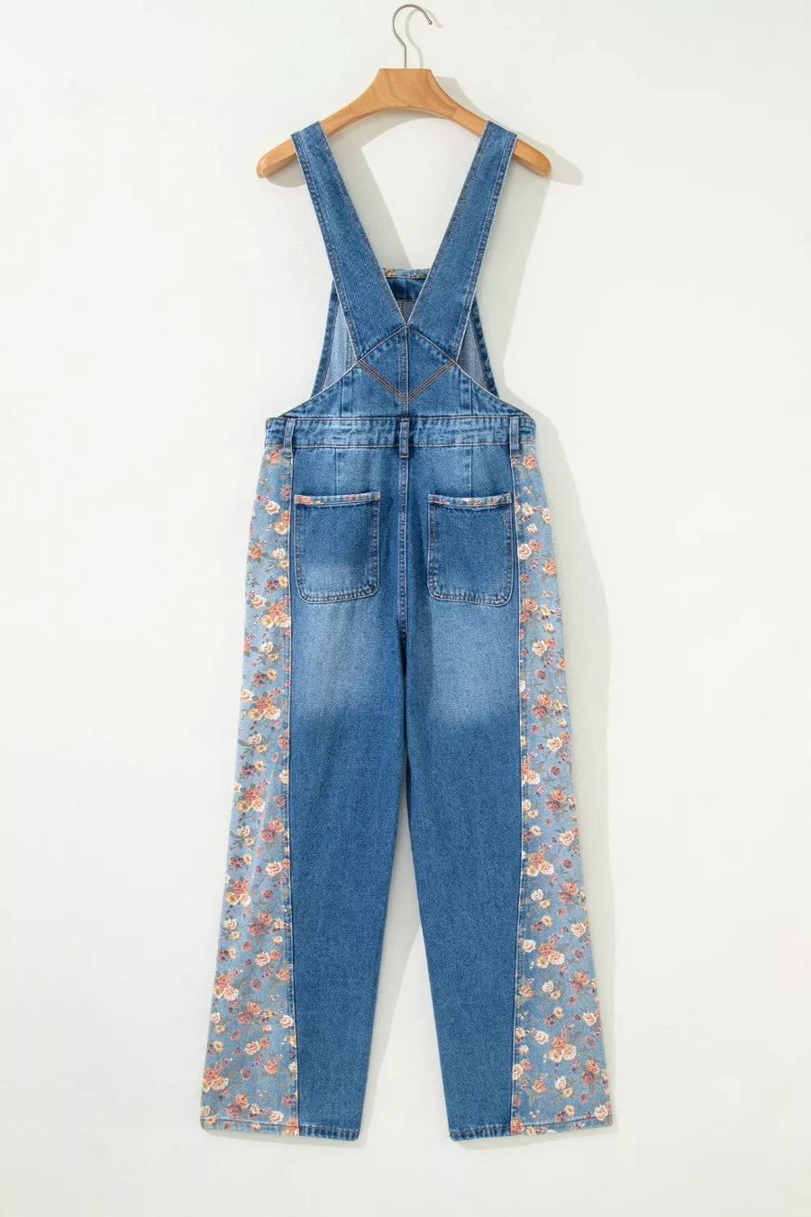 Blue denim overalls with floral patterns on a white background
