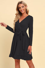 Woman wearing a black long-sleeve dress against a beige background