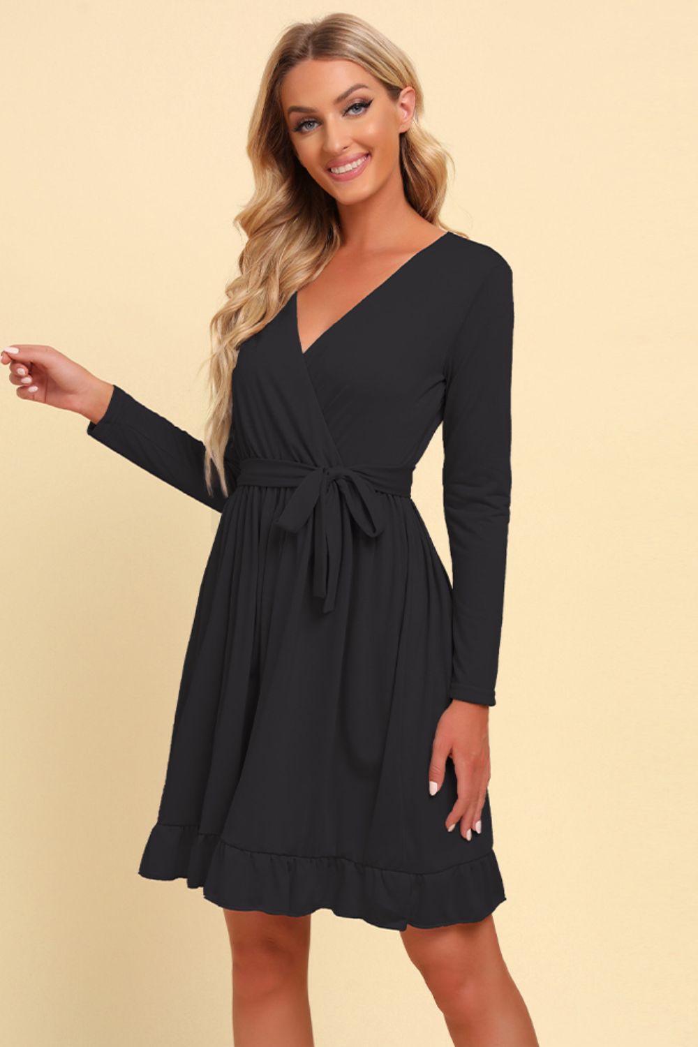 Woman wearing a black long-sleeve dress against a beige background