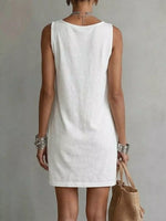 Person wearing a white sleeveless dress against a plain background