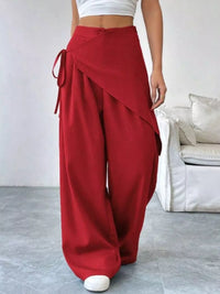 Red wide-leg pants worn by a person in a minimal indoor setting.