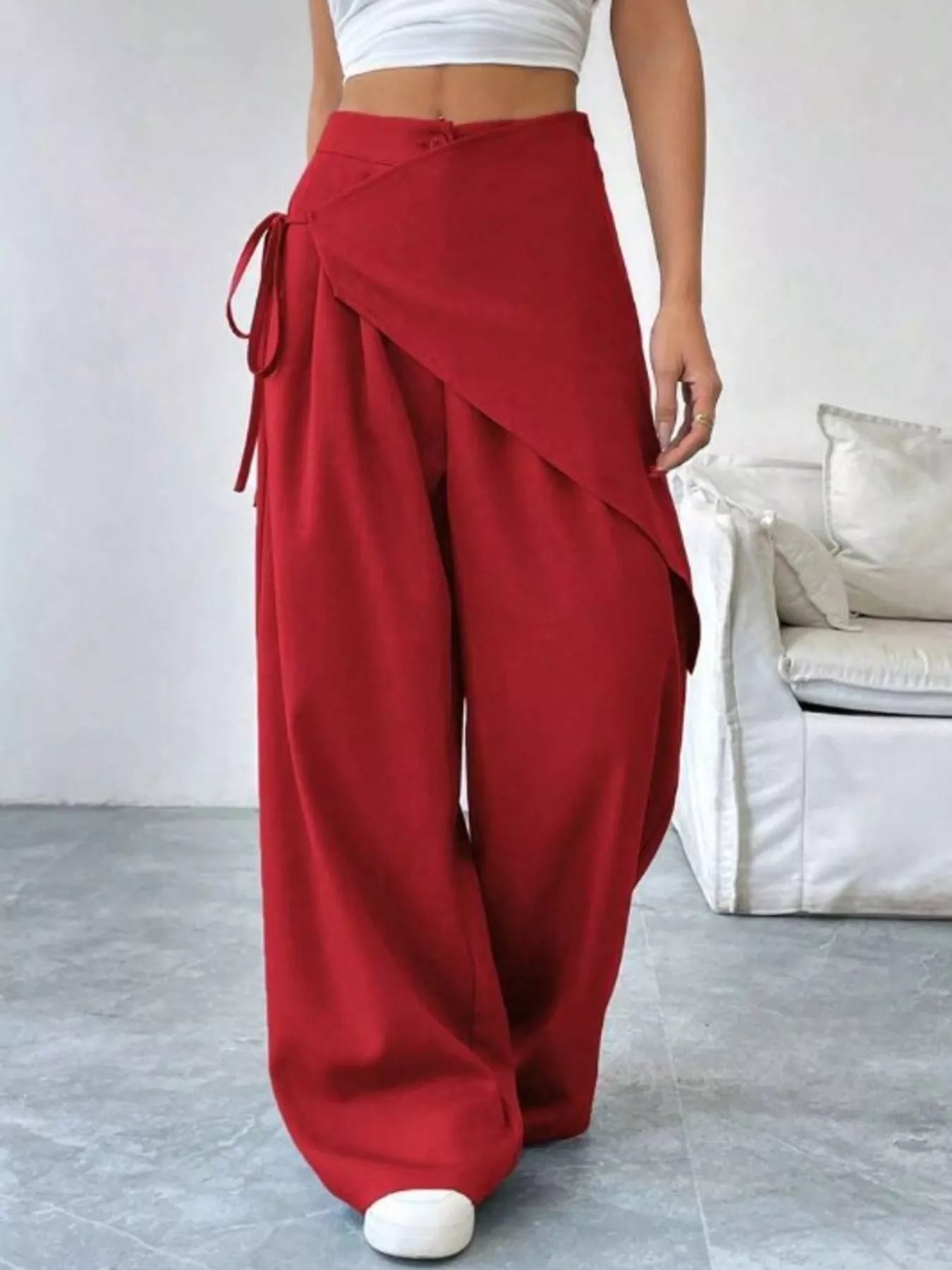 Red wide-leg pants worn by a person in a minimal indoor setting.