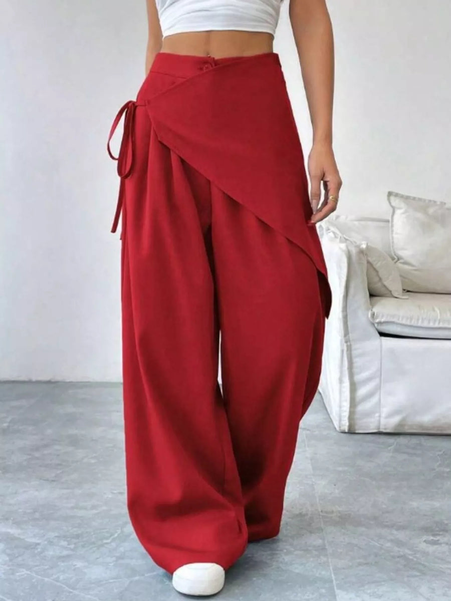 Red wide-leg pants worn by a person in a minimal indoor setting.