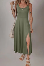 Woman wearing a green dress with a slit, standing against a plain background