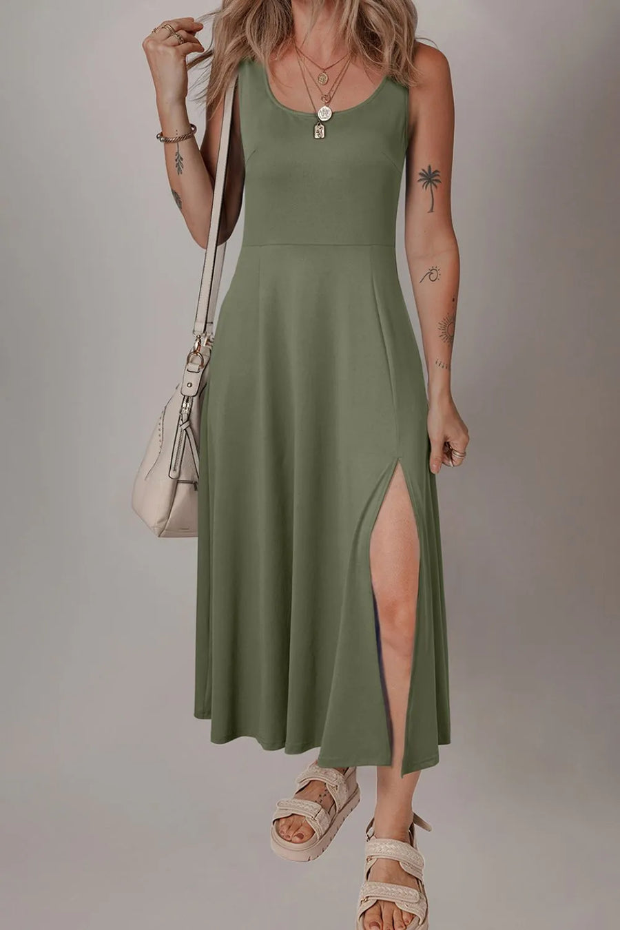 Woman wearing a green dress with a slit, standing against a plain background