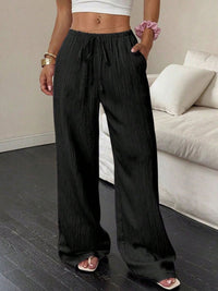 Person wearing black wide-leg pants in a living room setting