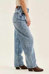 Person wearing light blue jeans and brown boots on a plain background