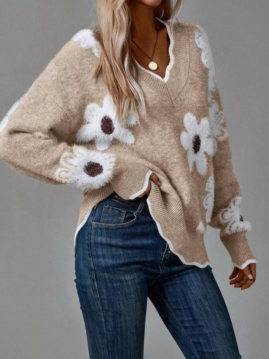 Beige sweater with floral patterns worn by a person on a gray background