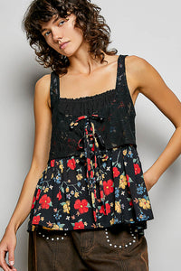 Woman wearing a black floral peplum top against a plain background
