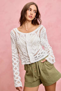 Woman wearing a white lace top and green shorts against a pink background