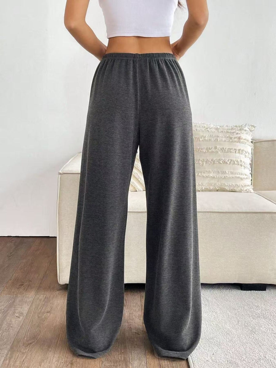 Person wearing gray wide-leg pants in a living room setting