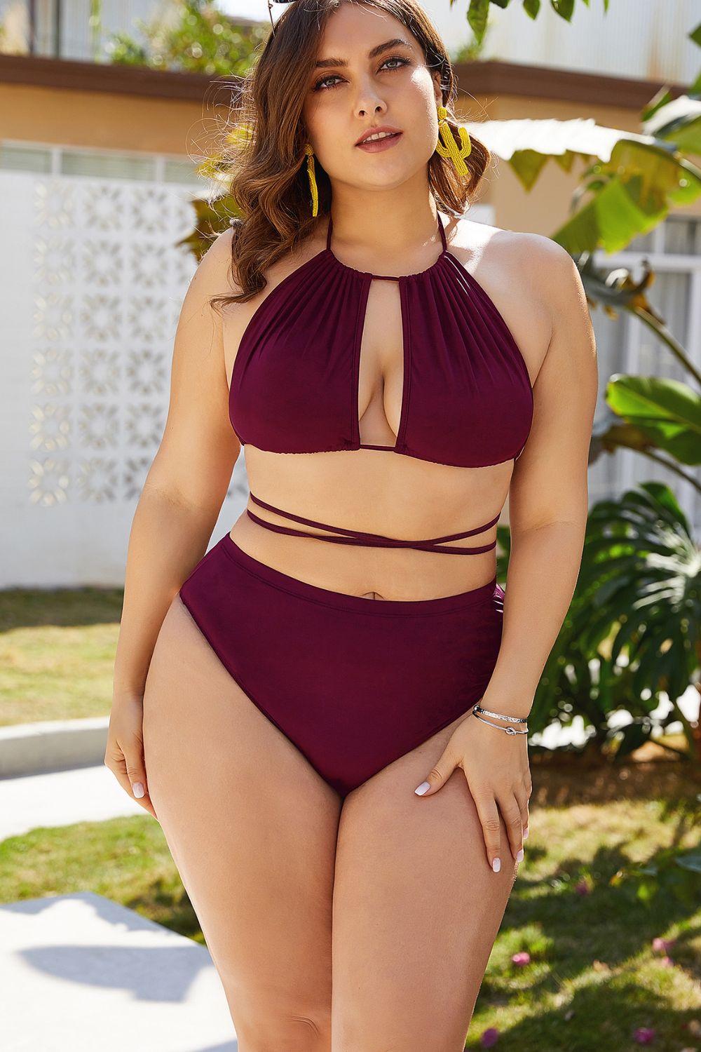 Woman wearing a burgundy bikini set outdoors with greenery in the background