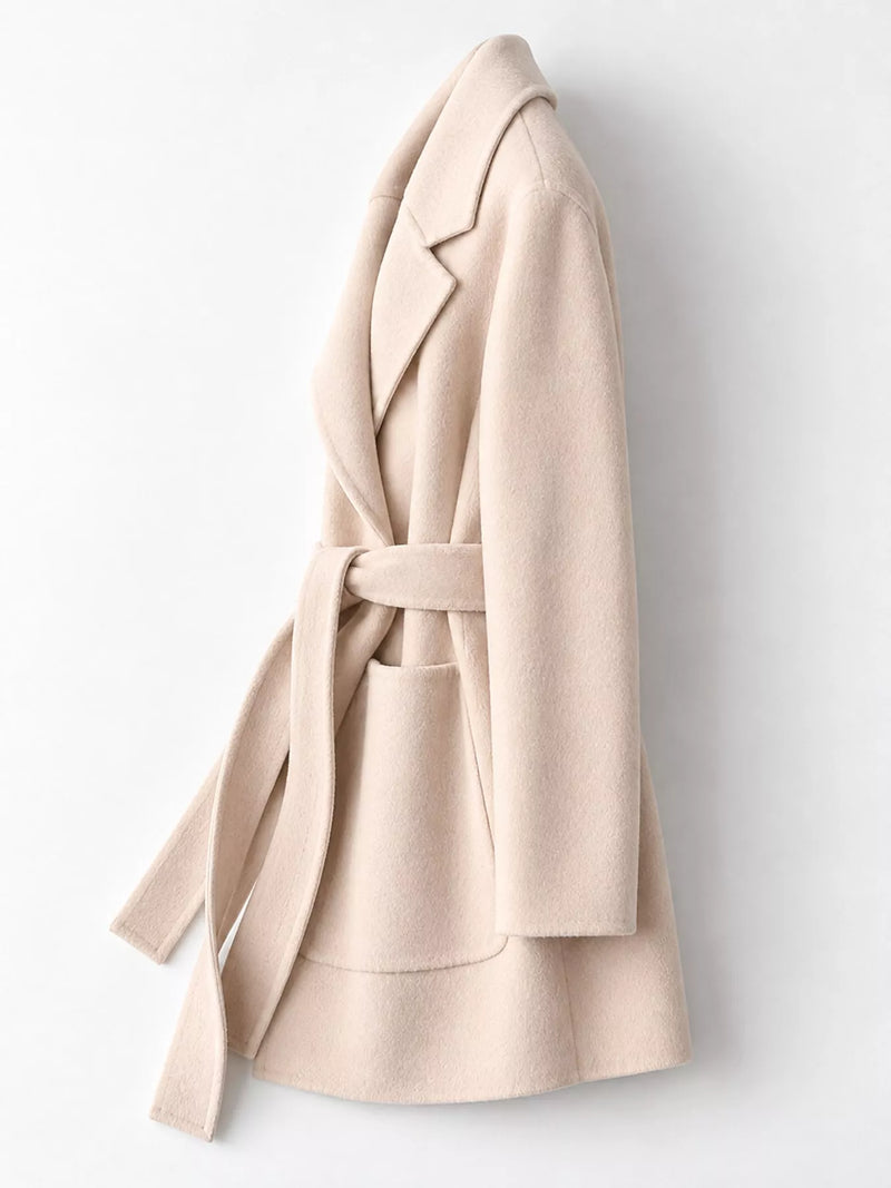 A light beige wool wrap coat with a matching waist tie belt and front patch pocket, shown from a side profile view against a plain white background.