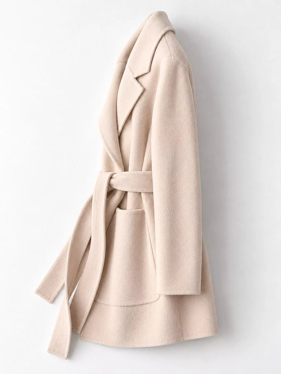 A light beige wool wrap coat with a matching waist tie belt and front patch pocket, shown from a side profile view against a plain white background.