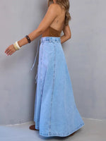 Person wearing a long denim skirt against a plain background