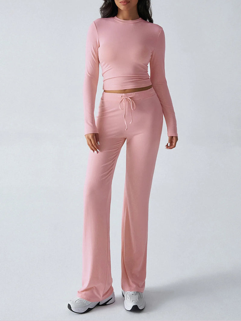 Person wearing a pink long-sleeve top and pants on a light gray background