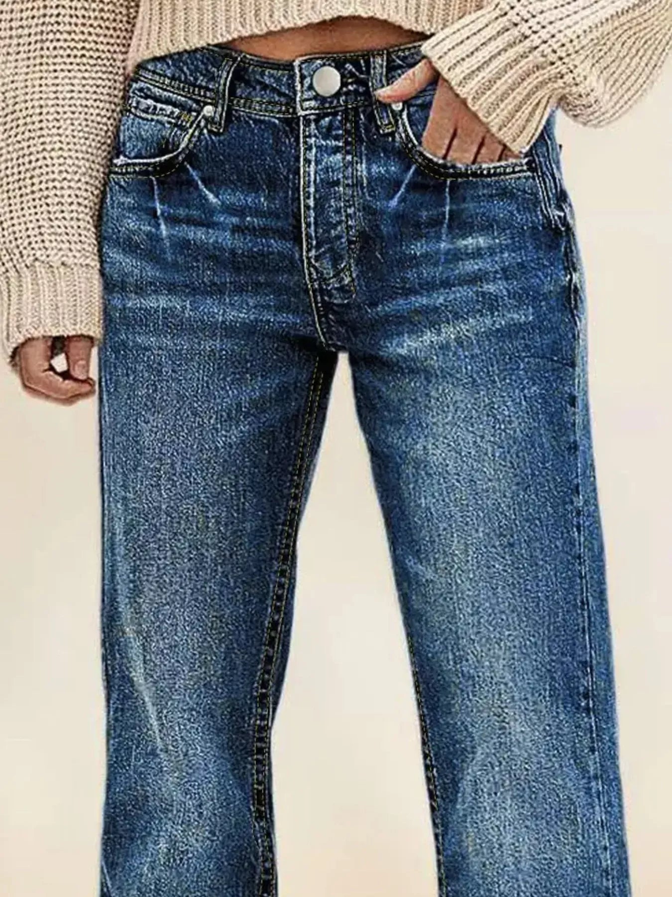 Blue jeans worn by a person on a plain background