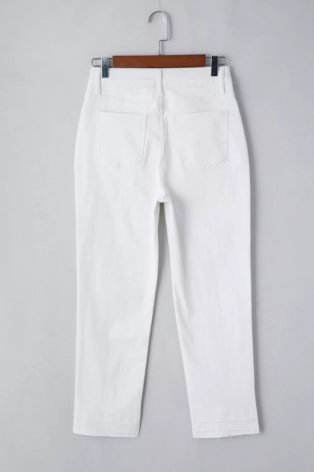 White pants on a hanger against a gray background