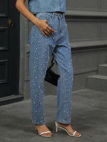 Person wearing pearl-studded blue jeans standing on steps.