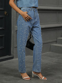 Person wearing pearl-studded blue jeans standing on steps.