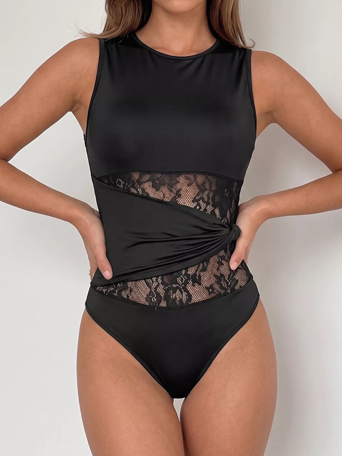 Black swimsuit with lace detailing on a plain background