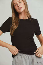 Woman wearing a black t-shirt and gray pants on a plain background