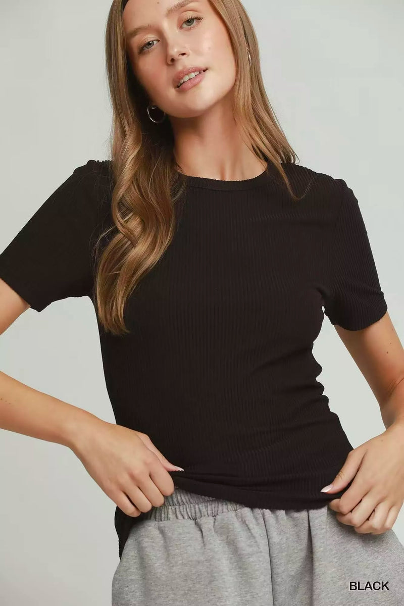 Woman wearing a black t-shirt and gray pants on a plain background