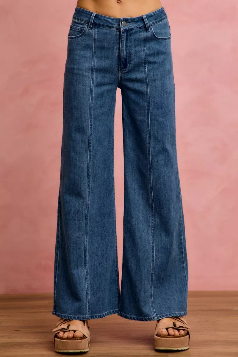 Wide-leg jeans worn by a person on a pink background