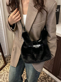 Person wearing a beige coat holding a black fur bag indoors.