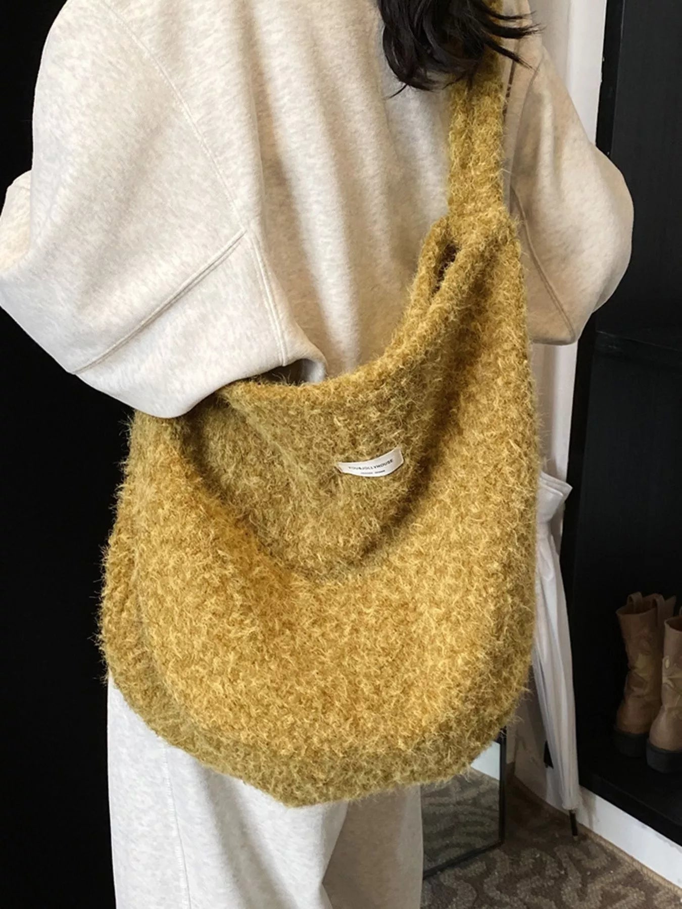 Person holding a mustard yellow textured handbag indoors.