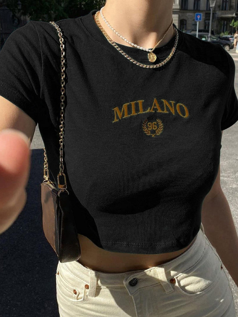 Person wearing a black t-shirt with 'MILANO' print, standing outdoors.
