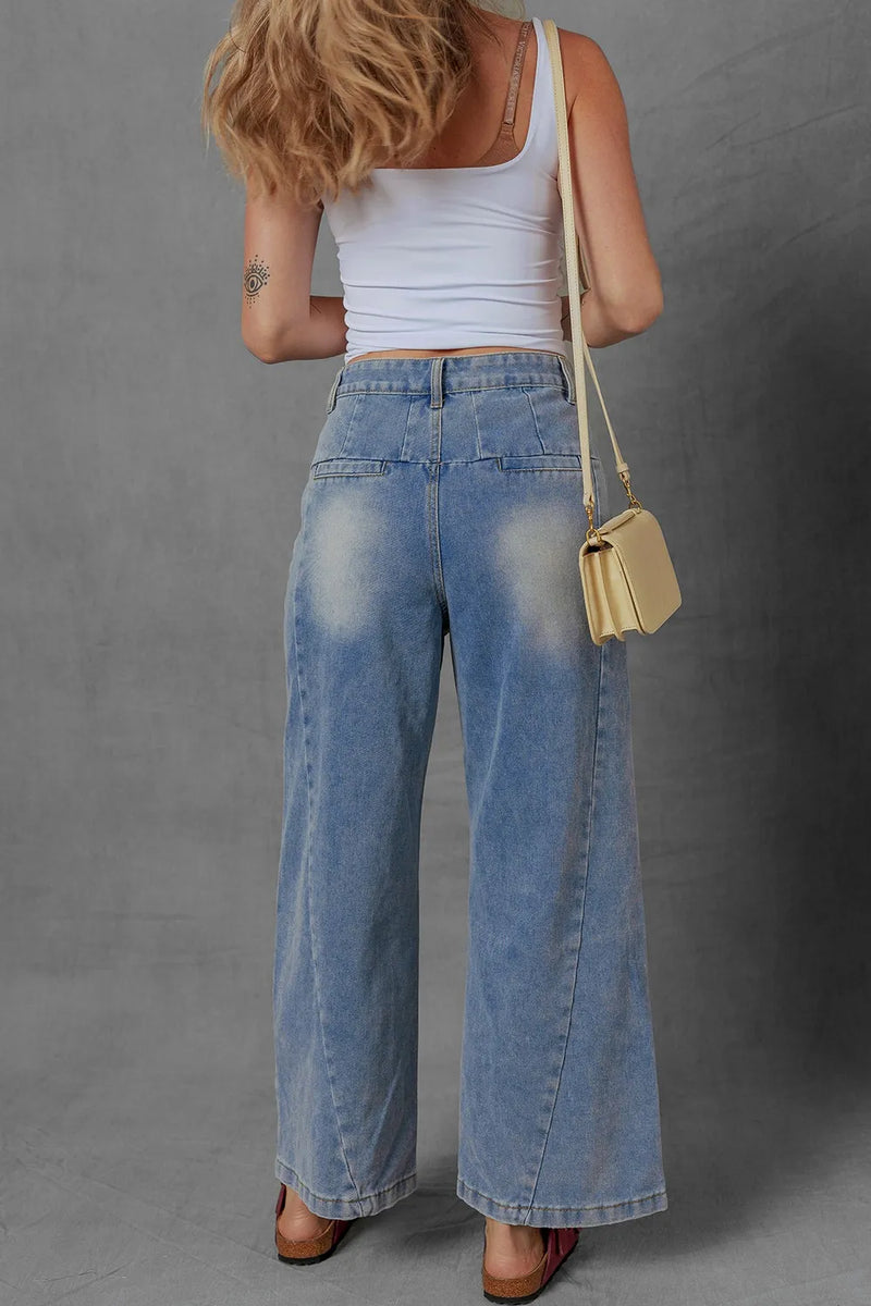 Person wearing a white tank top and blue jeans with a beige bag on a gray background