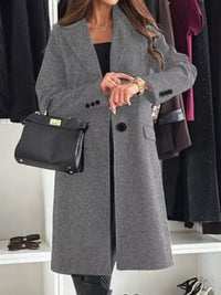 Person wearing a gray coat with a black handbag in a clothing store setting