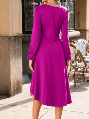 Person wearing a purple dress standing outdoors near a building entrance.
