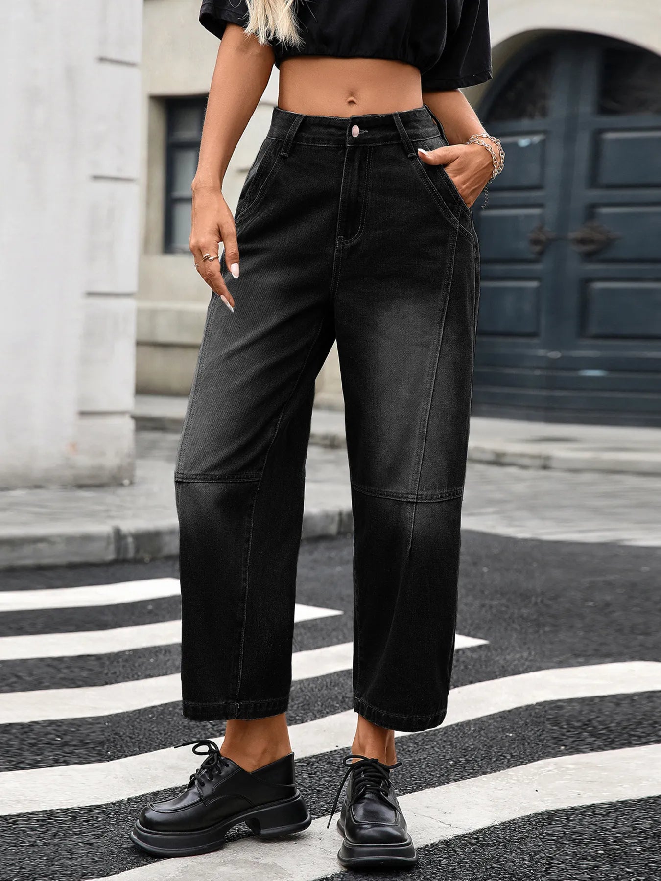 Person wearing black wide-leg jeans and black shoes on a street.